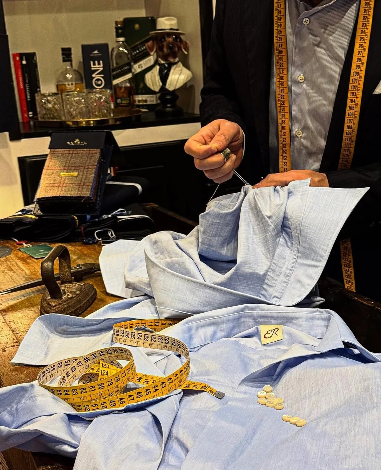 Lavorazione a mano di una camicia azzurra in atelier