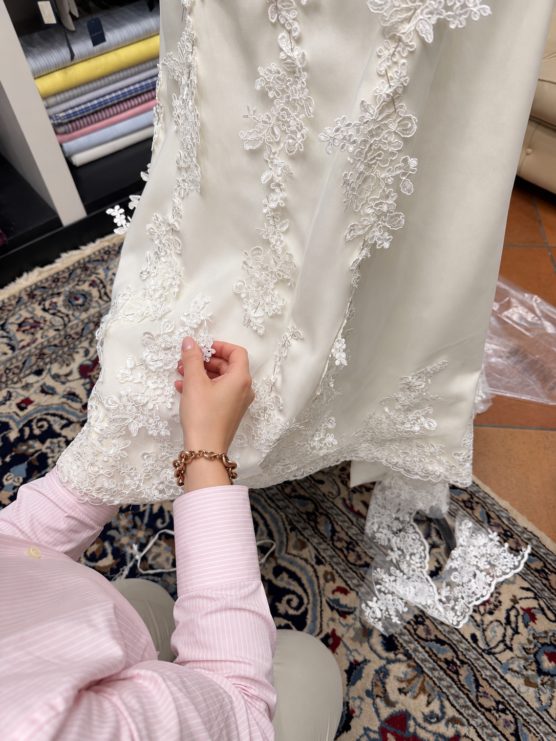 Mani al lavoro sul pizzo di un abito da sposa